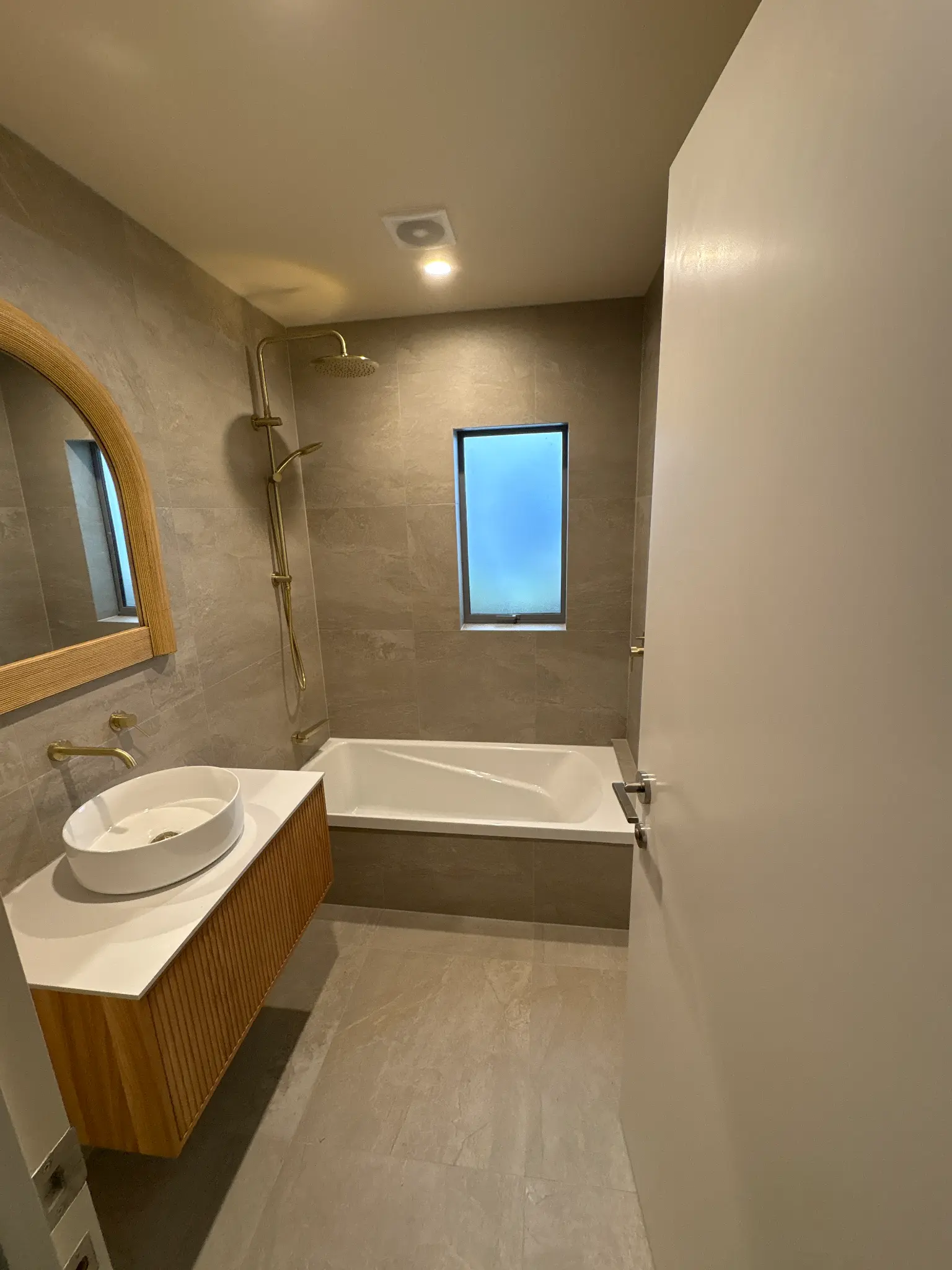 Completed bathroom with bath, vanity and tiled wall from an AA Bathrooms project